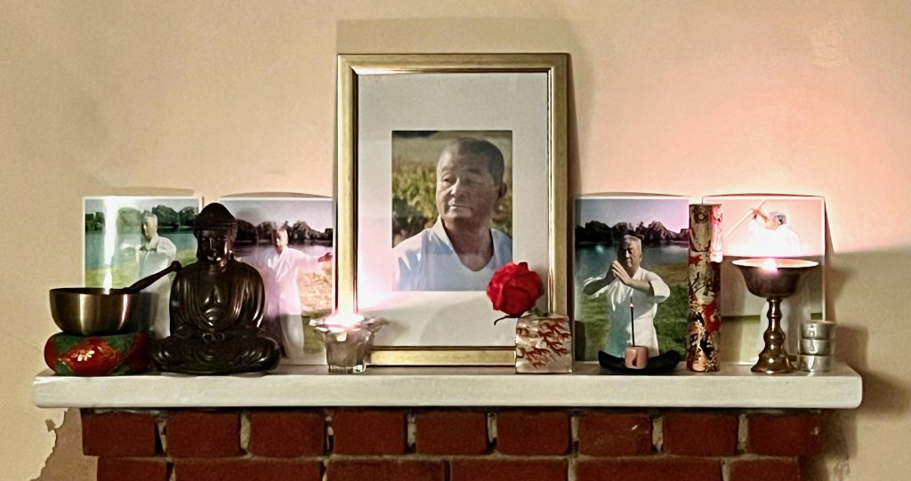 Photo of Haruyoshi Ito on a mantelpiece with flowers and statues