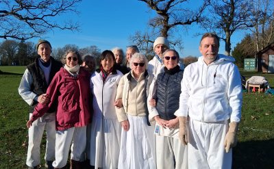 Group of Shintaido practitioners with warm clothing standing in a field under a bright blue sky